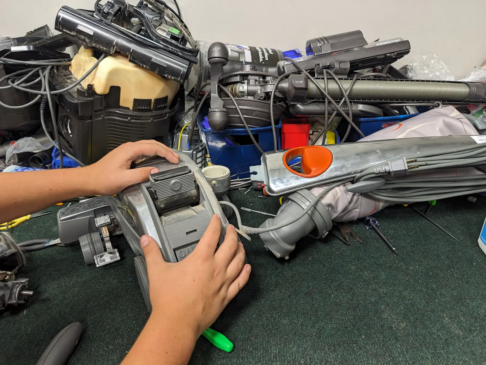 A vacuum opened up on the repair bench at Don's Sweeper, hands working on it, with more machines waiting behind.