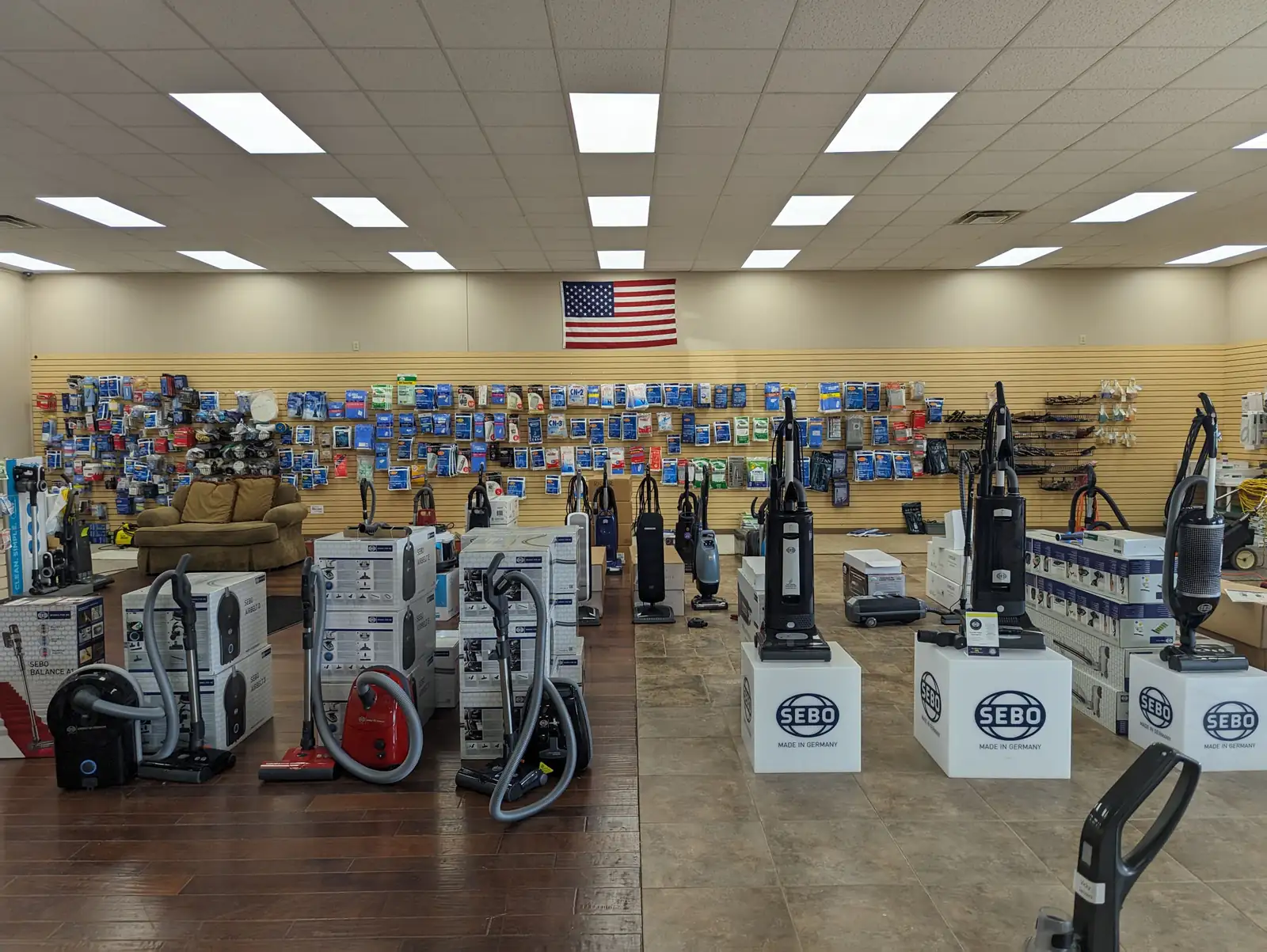 The sales floor at Don's Sweeper: a full wall of vacuum bags and filters across every brand, with uprights and canisters set out in front of it.